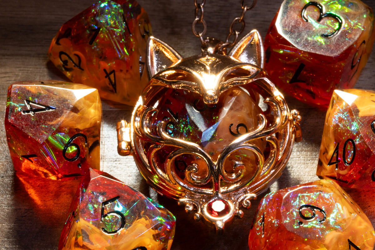 Close-up of the fox pendant in a copper finish holding an Amber Opal D20, with the Amber Opal dice set on wood