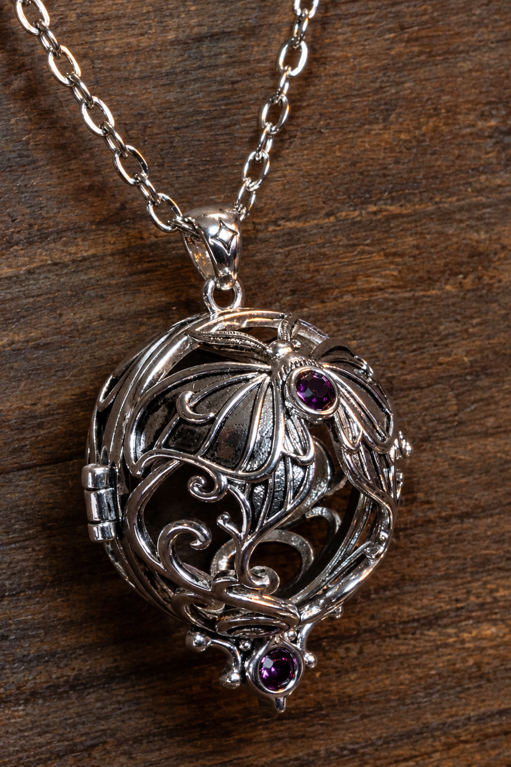 Lunar moth pendant in a silver finish shown empty on its chain, showing the openwork wings, scrolls, hinge and two purple crystals