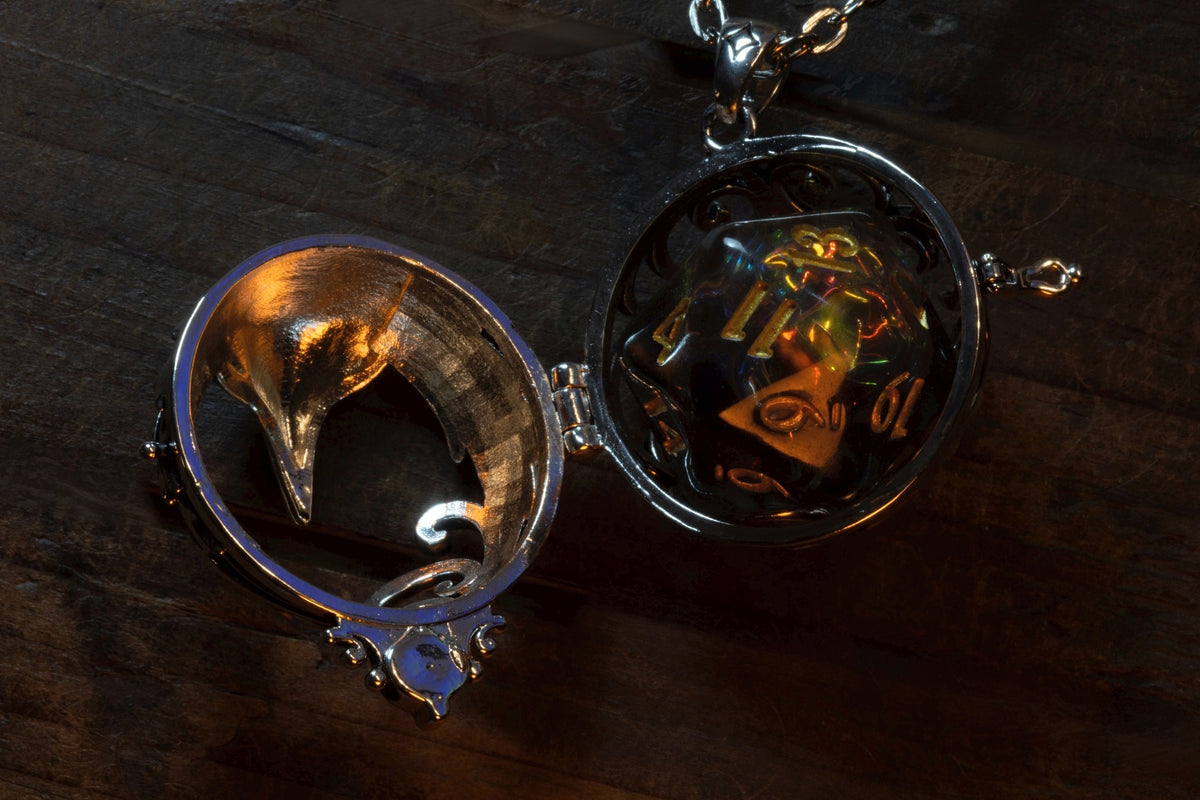 Raven pendant in a silver finish shown open on its hinge, a clear holographic D20 sitting inside, the raven lid lifted