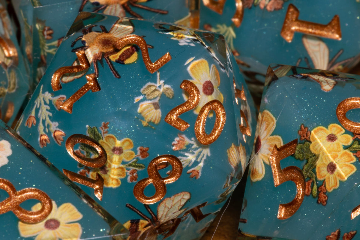 Honey Meadow Teal sharp edge dice close-up showing the bee and wildflower pattern