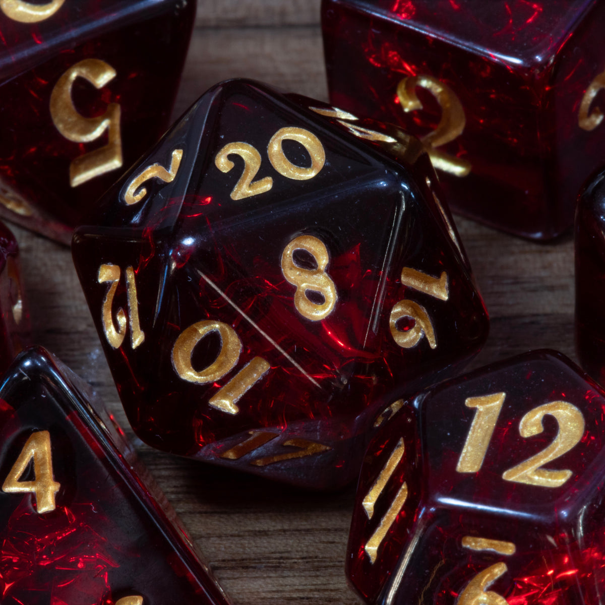 Close-up of a Cherry Opal D20 and dice, dark red resin with gold numbers
