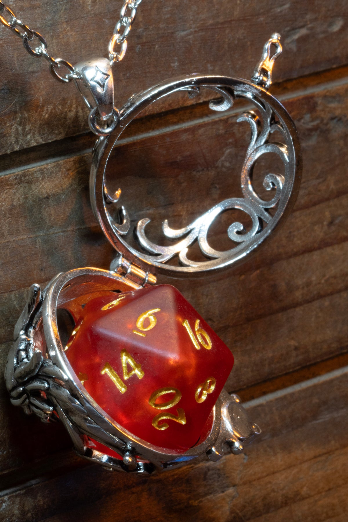 Dragon pendant in a silver finish shown open on its hinge, a red D20 sitting inside, the scrollwork back lifted