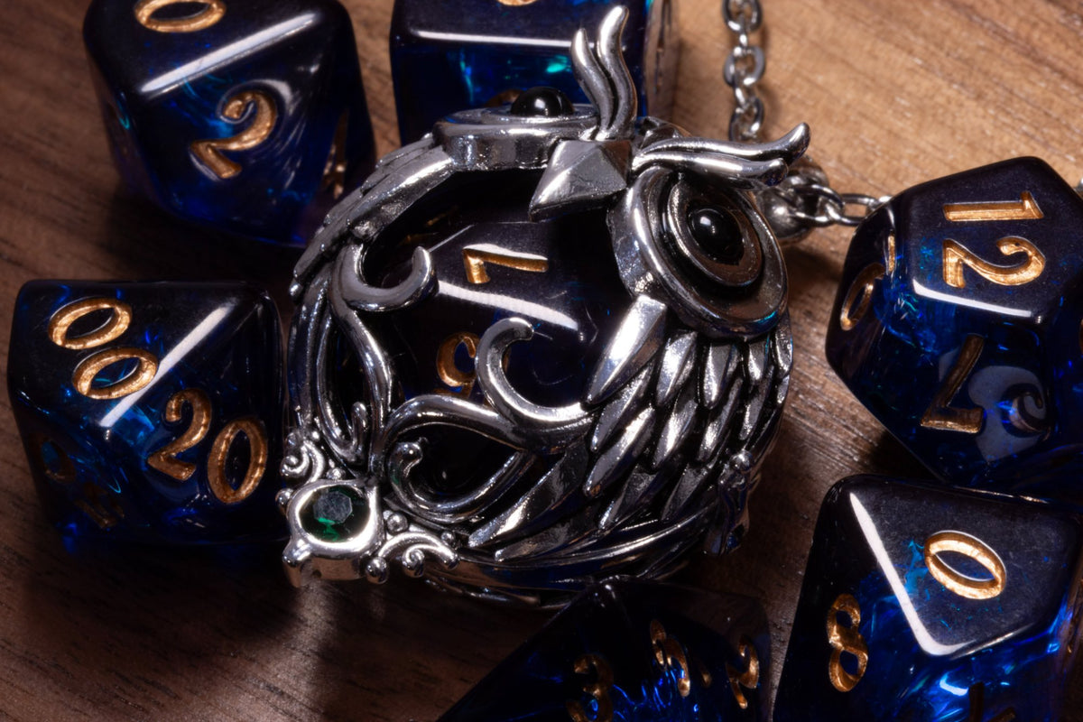 Close-up of the owl pendant in a silver finish, feathered wings and scrolls over a dark blue D20
