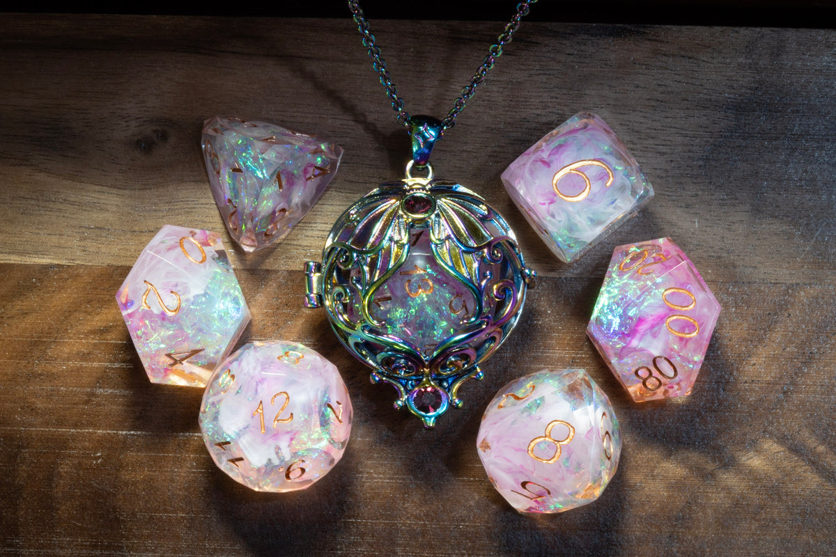 Lunar moth pendant in a rainbow finish with the Blush Opal dice set on wood