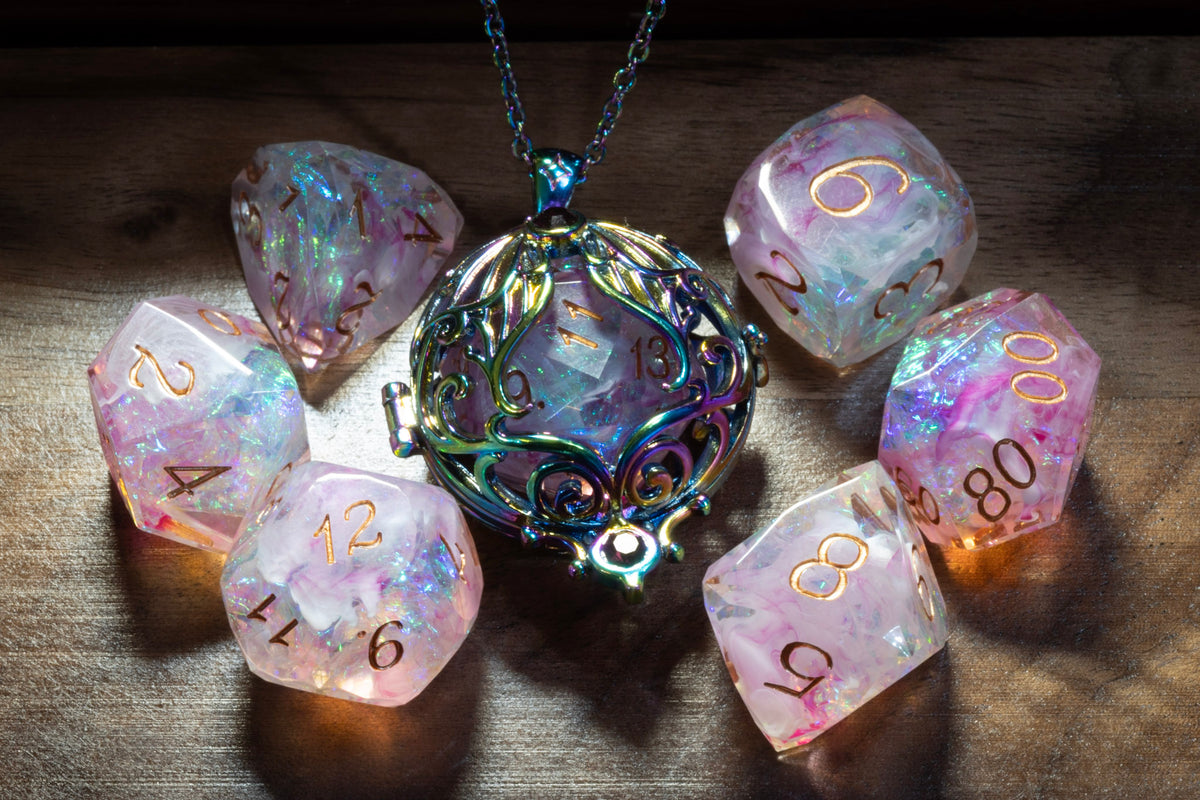 Lunar moth pendant in a rainbow finish with the Blush Opal dice set on wood